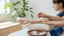 Mains d'un acupuncteur posant une aiguille fine sur l'avant-bras d'une femme, en cabinet