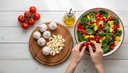 Mains disposant de l'ail frais et de légumes méditerranéens sur une table en bois, scène de nutrition cardiovasculaire