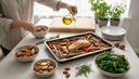 Vue plongeante sur des mains versant de l huile d olive sur des legumes rotis et un pave de saumon
