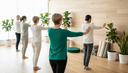 Un petit groupe d'adultes vus de dos enchaîne un mouvement lent de tai-chi dans un studio de bien-être