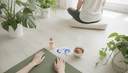 Vue plongeante sur des mains disposant tapis, flacon sans étiquette, cartes de respiration et tasse