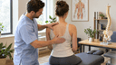 Chiropracteur évaluant avec douceur l'alignement de la colonne vertébrale d'un patient assis lors d'un bilan de scoliose