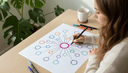 Mains dessinant au feutre un schéma de cercles reliés sur une grande feuille, vue de dessus