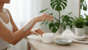 Gros plan de mains étalant une crème le long d'un avant-bras, pot ouvert et linge roulé sur une coiffeuse
