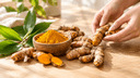 Racines et poudre de curcuma doré dans un bol sur une table en bois clair, évoquant une approche naturelle pour la peau