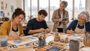 Groupe d’adultes en formation d’art-thérapie peignant et modelant l’argile sous le regard attentif d’une formatrice