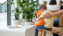 Gros plan d'une main de parent posée sur le dos d'un enfant serrant une peluche sur une chaise