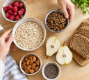 Aliments riches en fibres vus de dessus sur un plan de travail en bois : avoine, lentilles, framboises, poire et amandes