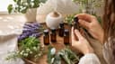 Vue plongeante de mains ouvrant un coffret de fioles entouré de brins de plantes aromatiques