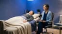 Mains tenant un casque de réalité virtuelle au-dessus d'un fauteuil de soin, écouteurs et flacon