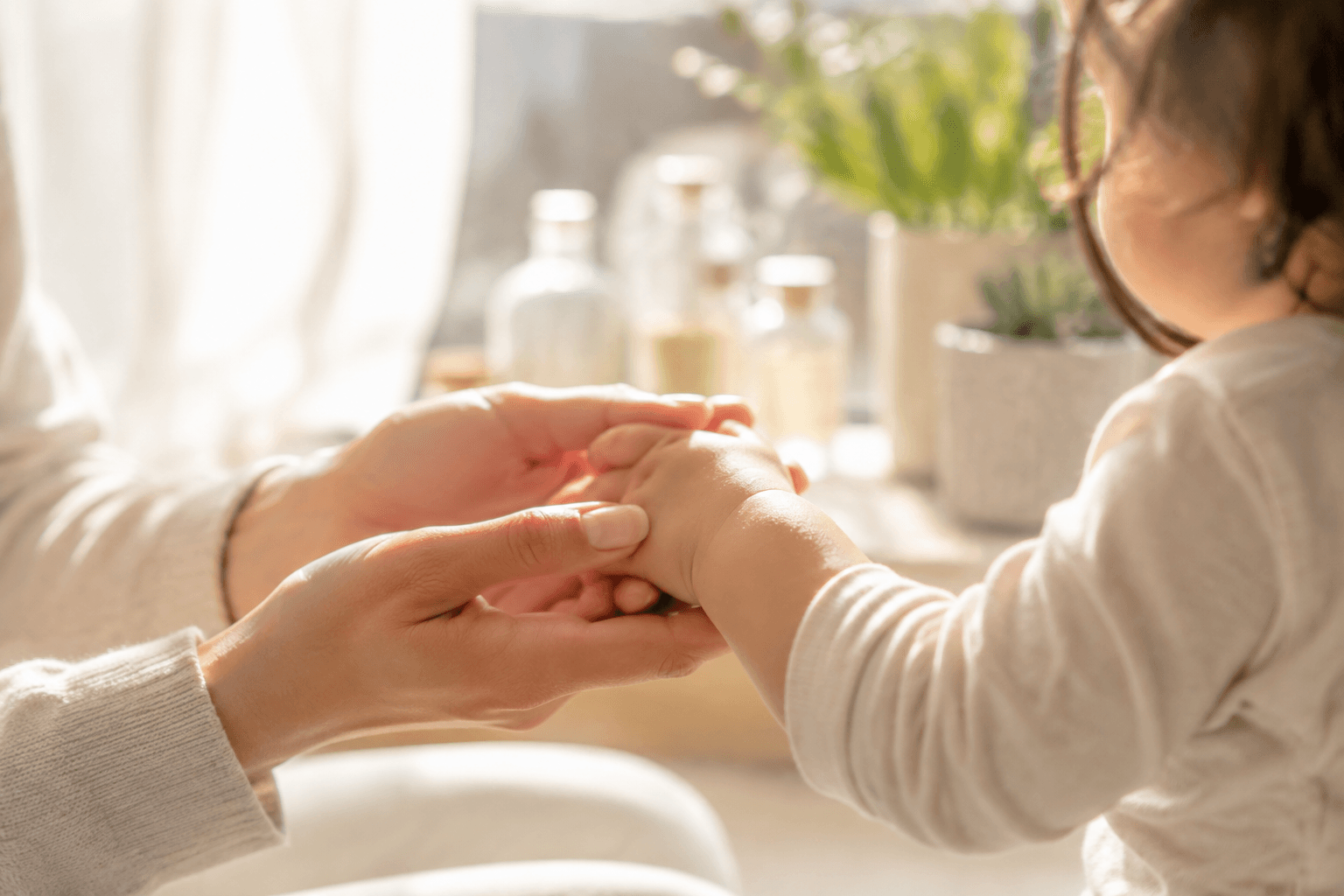 Mains d'un parent tenant doucement la main d'un jeune enfant à la maison, ambiance chaleureuse et rassurante