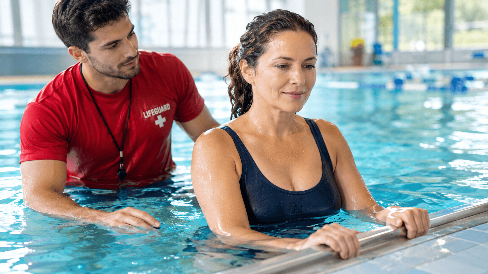 Adulte débutant serein au bord d'une piscine, guidé par un maître-nageur, illustrant le dépassement de la peur de l'eau