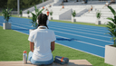 Coureuse assise de dos sur un banc de stade, casque autour du cou, gourde et serviette roulée
