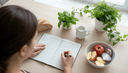 Vue plongeante sur des mains remplissant un carnet alimentaire près de pain, lait et pommes