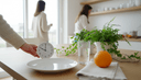 Vue plongeante sur des mains posant une horloge près d'une assiette vide et d'un verre d'eau