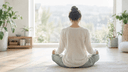 Personne de dos en méditation assise près d'une fenêtre lumineuse, atmosphère apaisante évoquant l'apaisement de l'anxiété
