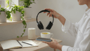 Gros plan de mains tenant un casque audio au-dessus d'un téléphone retourné sur une table