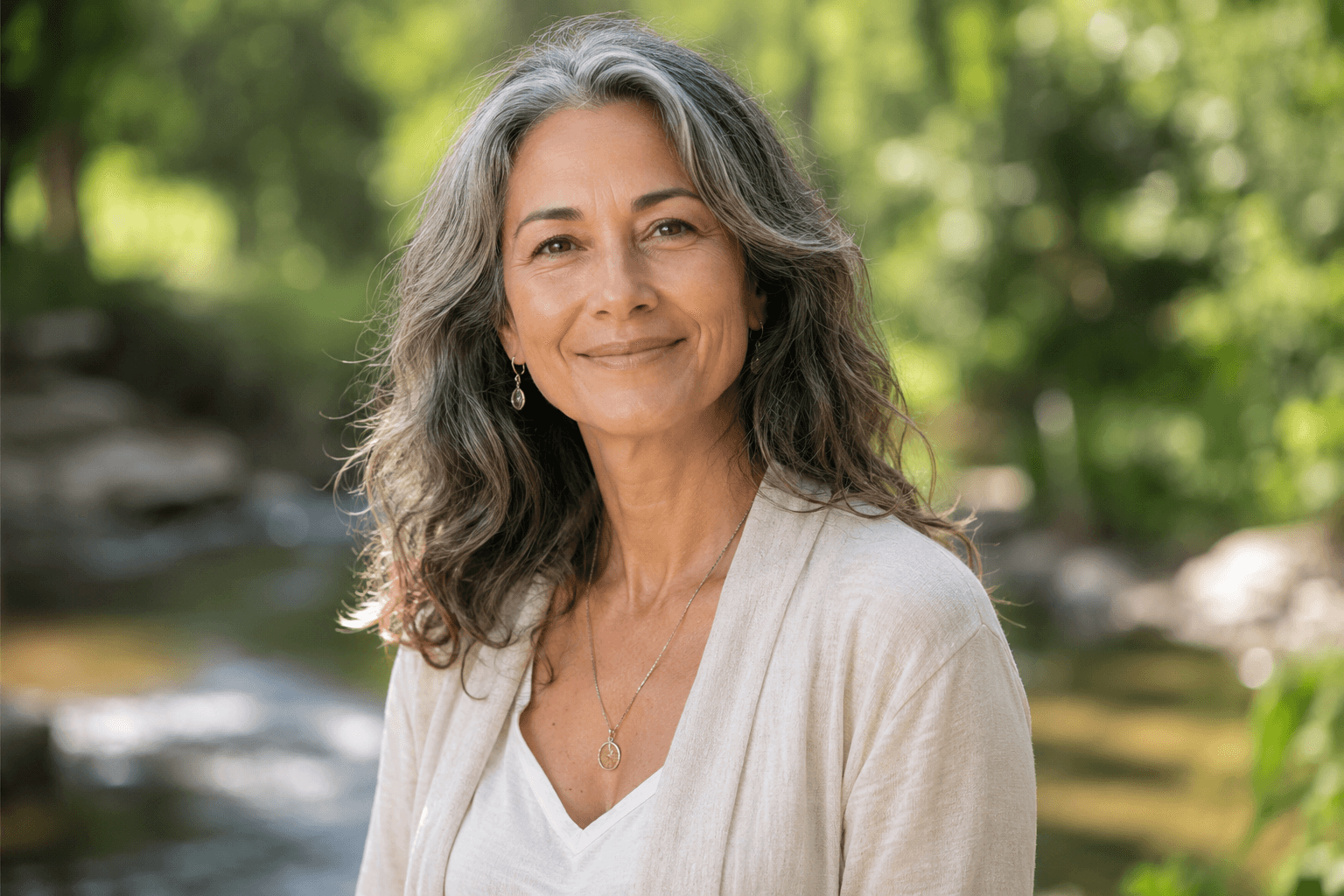 Femme d'une cinquantaine d'années sereine et pleine de vitalité, en extérieur dans un cadre naturel apaisant