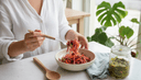 Vue plongeante de mains servant des légumes fermentés d'un bocal dans un bol en cuisine
