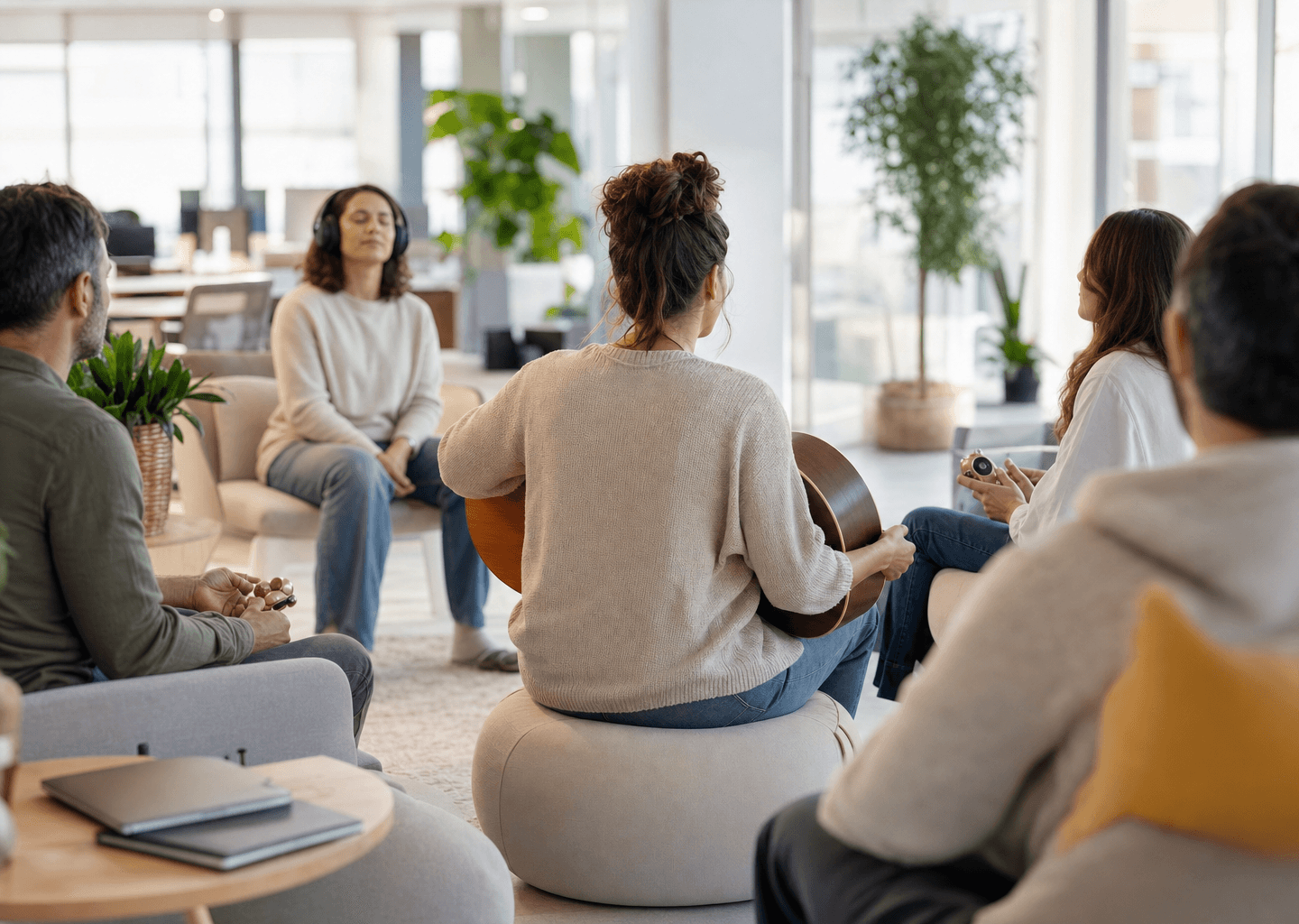 Atelier de musicothérapie en entreprise : salariés détendus en cercle avec un musicothérapeute dans un open-space lumineux