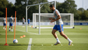 Joueur de football de profil enchaînant un exercice d'échelle de coordination sur le terrain