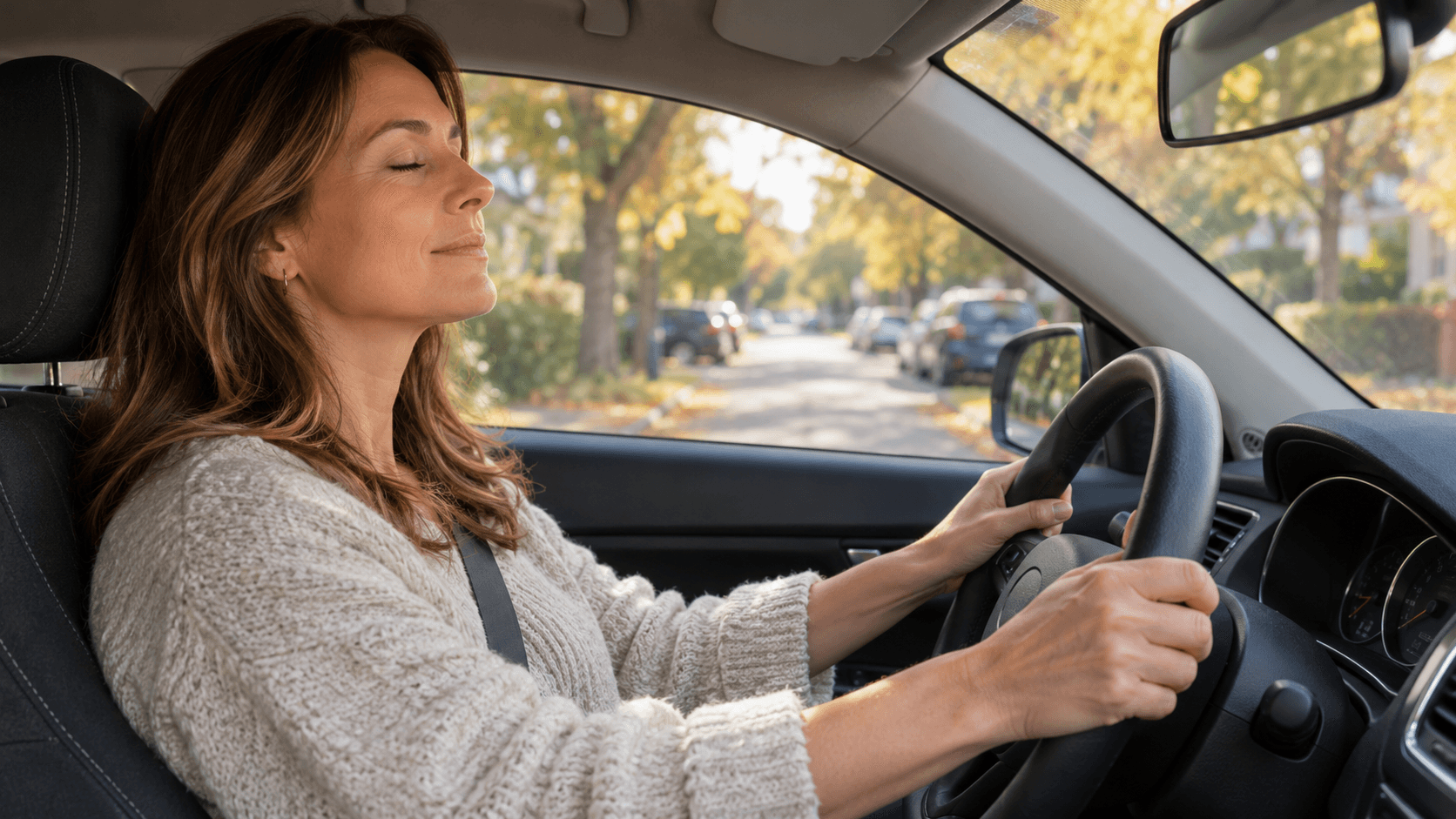 Femme au volant d’une voiture à l’arrêt, mains posées sur le volant, qui respire calmement avant de reprendre la route