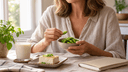 Femme d'une cinquantaine d'années à une table de cuisine tenant un bol d'edamame, avec du tofu et une boisson au soja