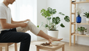 Mains enveloppant un cataplasme de lin autour d'un genou, racines d'harpagophytum séchées sur un tabouret
