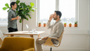 Homme de profil assis sur une chaise, une main aux narines, dans une salle de pause