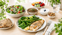 Assiette du régime DASH : poisson grillé, légumes verts, salade, pain complet, lentilles et fruits sur une table en bois