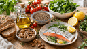 Aliments du régime méditerranéen sur une table en bois : huile d'olive, légumes, poisson frais, noix et légumineuses