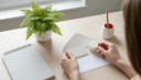 Vue plongeante sur des mains glissant une carte vierge et une bougie dans une enveloppe