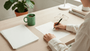 Vue plongeante sur des mains remplissant une fiche à trois colonnes sur un bureau, tasse à côté