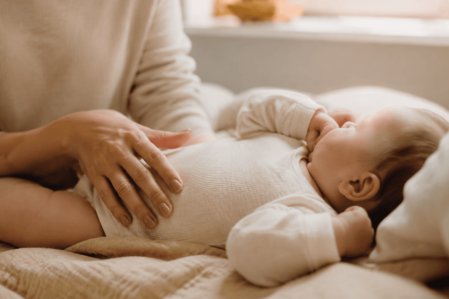Parent apaisant tendrement son bébé à la maison dans une lumière douce, évoquant le soulagement des troubles digestifs du nourrisson